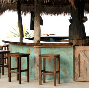 Three bar stools at a turquoise painted bar with thatched roof
